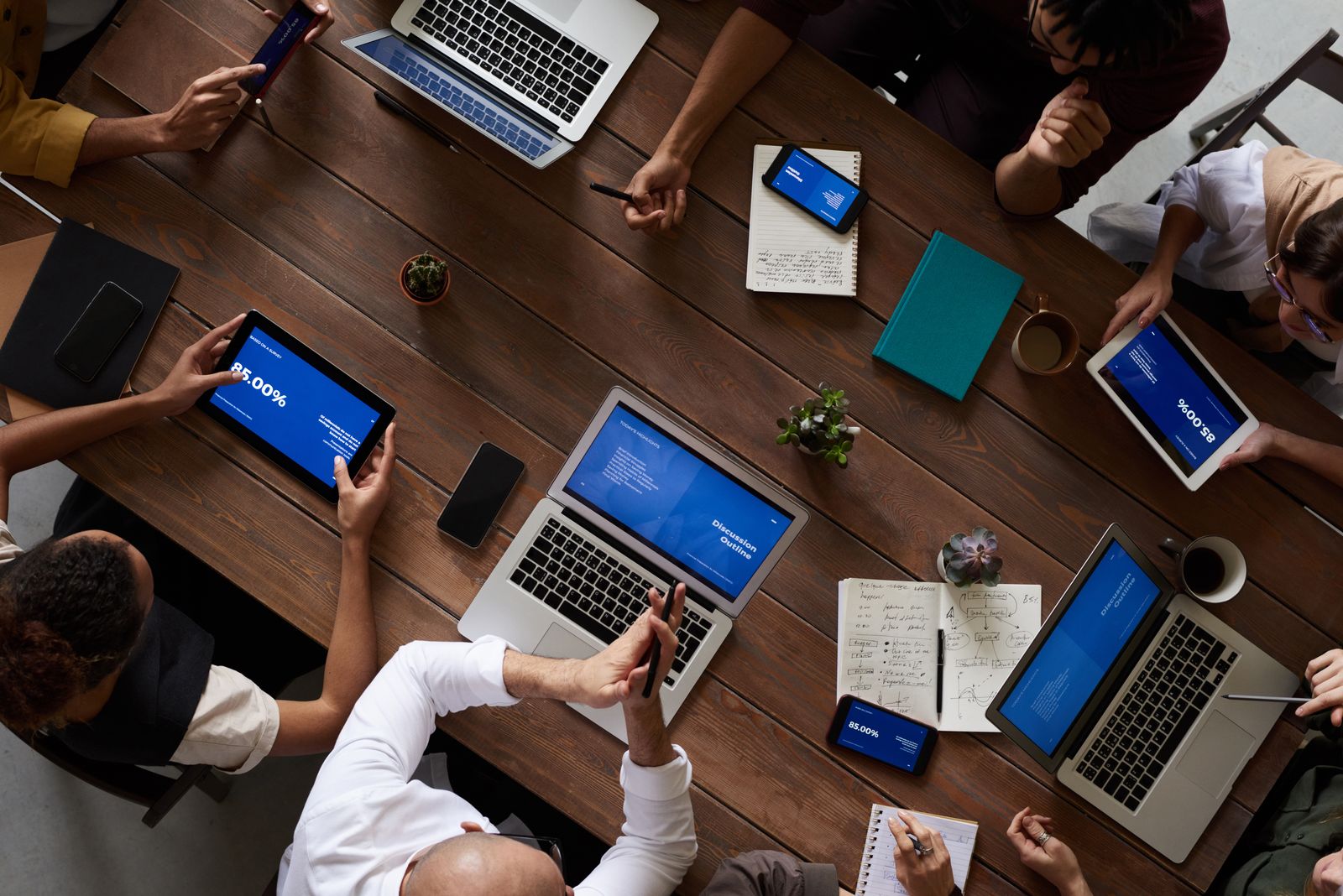 Ein Team bespricht Zahlen an einem Tisch, Laptops und Notizen nebeneinander.